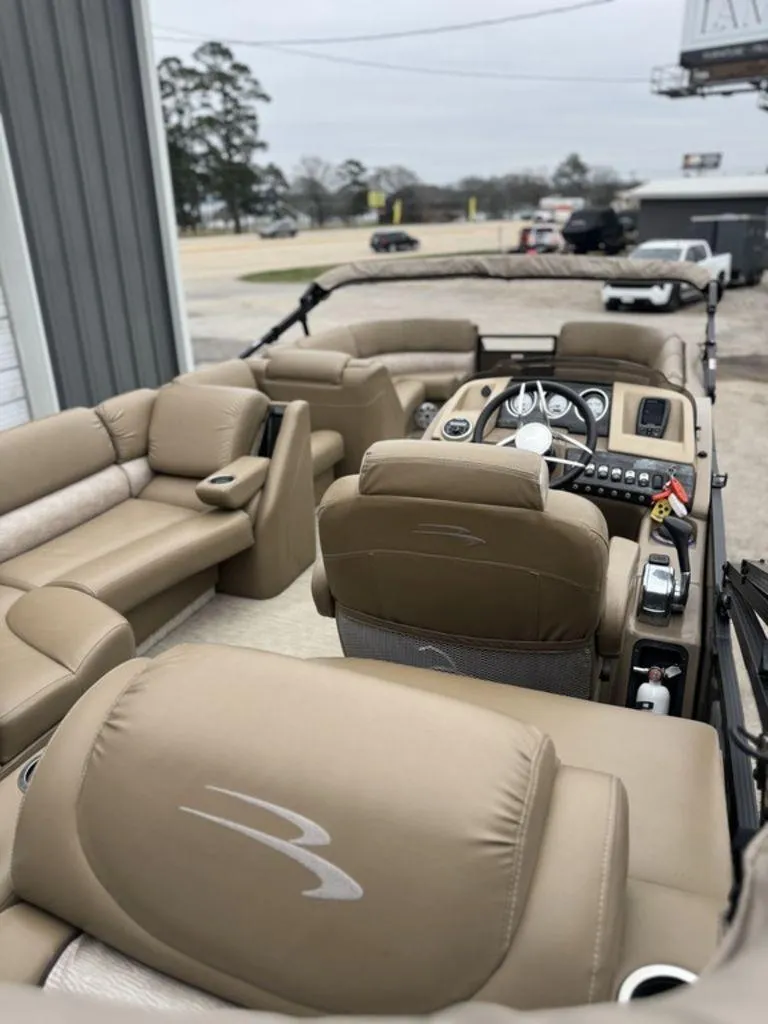 Slide: The Image of 2016 Bennington 2575 QCW I/O boat interior with beige seating and control panel. - 12