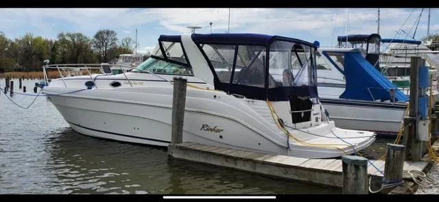 The Image of 2004 Rinker Fiesta Vee 342 docked at a marina, featuring a sleek white design. - 0