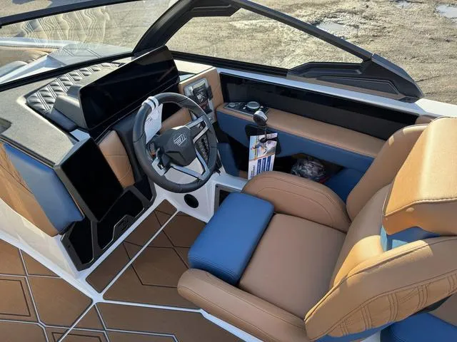 Slide: The Image of 2025 Malibu M230 boat interior with modern dashboard, steering wheel, and tan seating. - 20