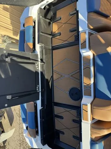 Slide: The Image of 2025 Malibu M230 boat interior with blue and tan seating, open storage compartments. - 24