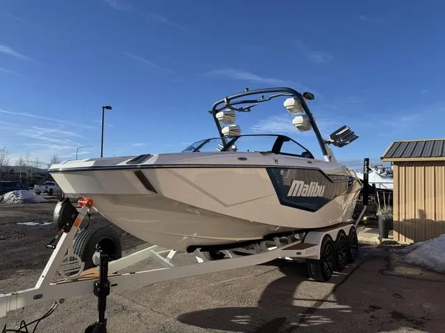 Slide: The Image of 2025 Malibu M230 boat on trailer, parked outdoors under clear blue sky. - 5