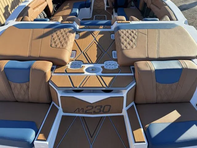 Slide: The Image of 2025 Malibu M230 boat interior with tan and blue seating, stylish design. - 8