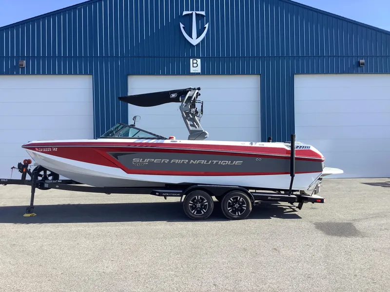 Slide: The Image of 2019 Nautique GS24 boat on trailer in front of blue building. - 1