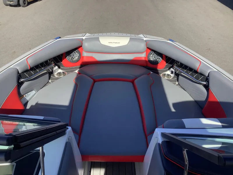 Slide: The Image of 2019 Nautique GS24 boat interior with gray and red seating, cup holders, and speakers. - 11