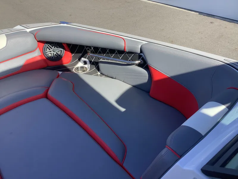 Slide: The Image of 2019 Nautique GS24 boat interior with gray and red seating, speaker, and cup holder. - 12