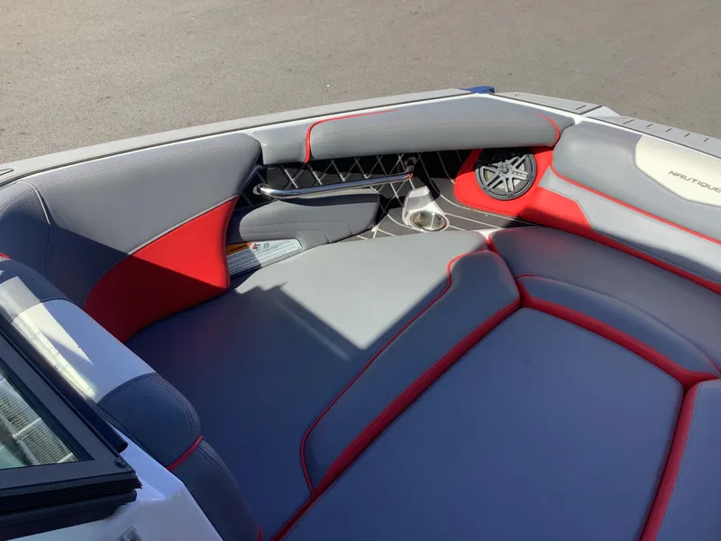 Slide: The Image of 2019 Nautique GS24 boat interior with gray and red seating, speaker, and cup holder. - 13
