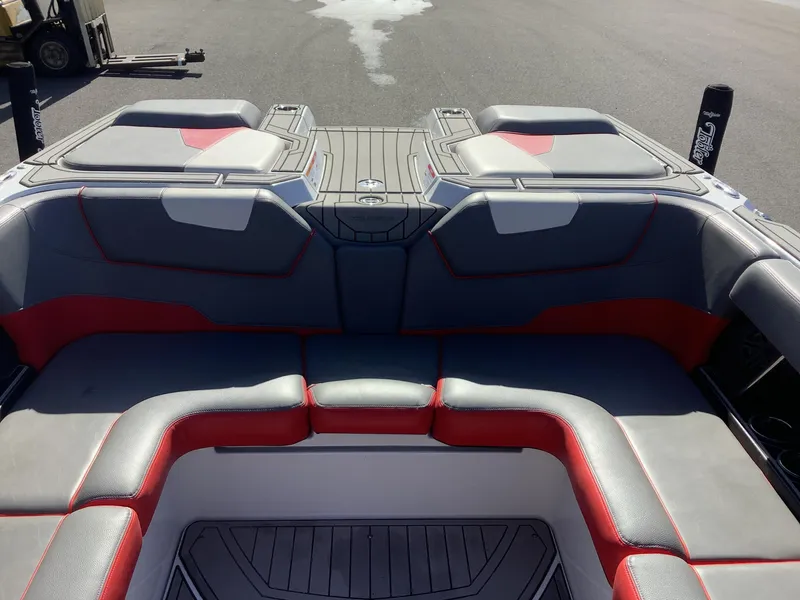 Slide: The Image of 2019 Nautique GS24 boat interior with gray and red seating, docked on pavement. - 16
