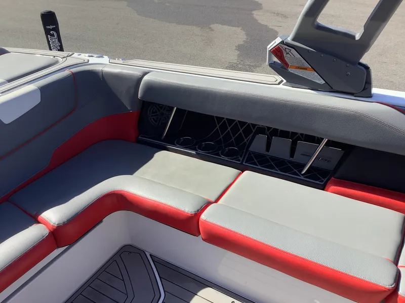 Slide: The Image of 2019 Nautique GS24 boat interior with gray and red seating, cup holders, and storage compartments. - 17