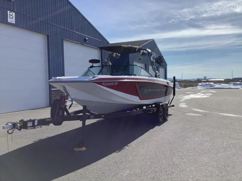 Slide: The Image of 2019 Nautique GS24 boat on trailer outside a warehouse. - 2