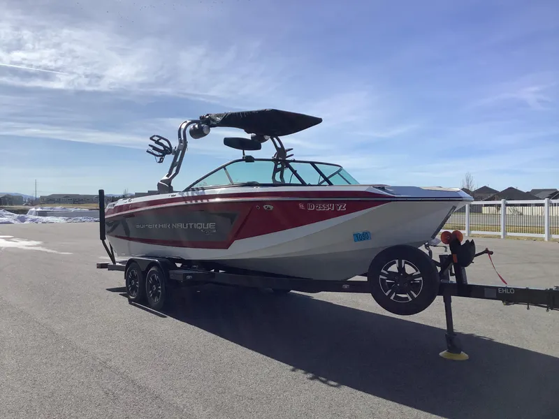 Slide: The Image of 2019 Nautique GS24 boat on trailer under clear blue sky. - 4