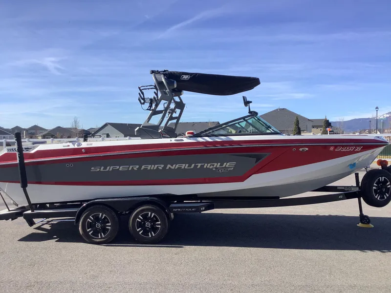 Slide: The Image of 2019 Nautique GS24 boat on trailer, red and gray design, parked outdoors. - 5