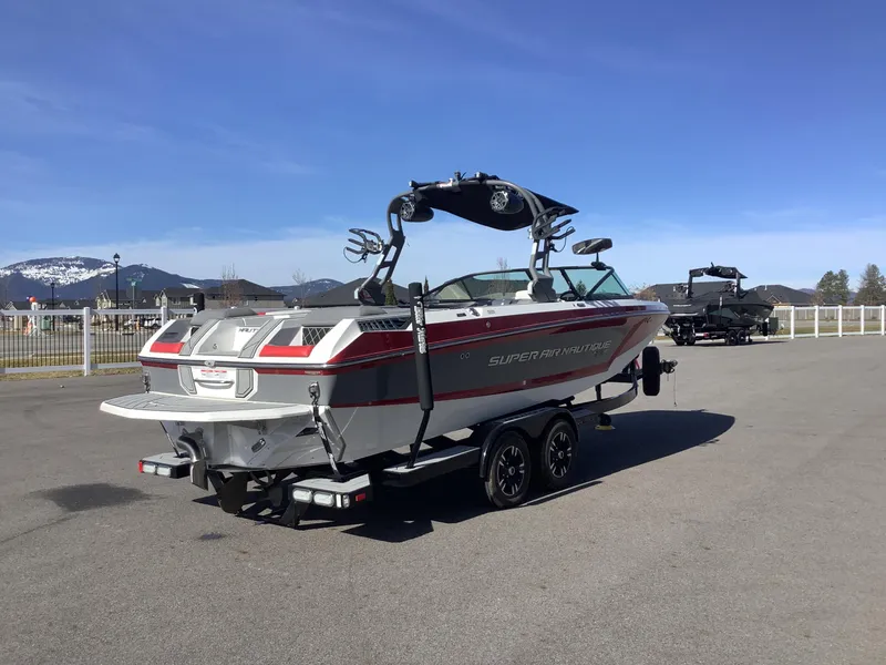 Slide: The Image of 2019 Nautique GS24 boat on trailer, parked outdoors with mountains in background. - 6
