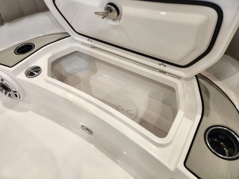 Slide: The Image of 2025 Sportsman Masters 267OE Bay Boat storage compartment with open lid and cup holders. - 10