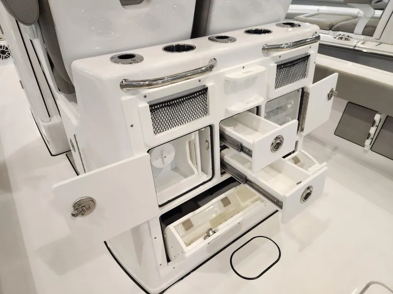 Slide: The Image of 2025 Sportsman Masters 267OE Bay Boat storage compartments with open drawers and cup holders. - 15