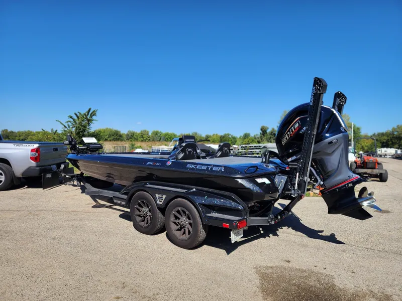 Slide: The Image of 2024 Skeeter FXR21LE boat with trailer, parked outdoors on a sunny day. - 2