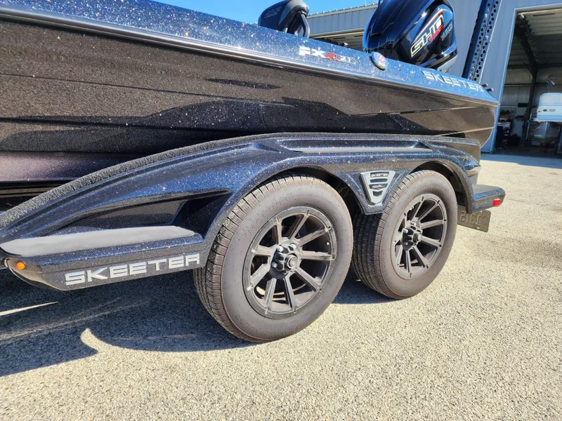 Slide: The Image of 2024 Skeeter FXR21LE boat trailer with black wheels and sleek design. - 9