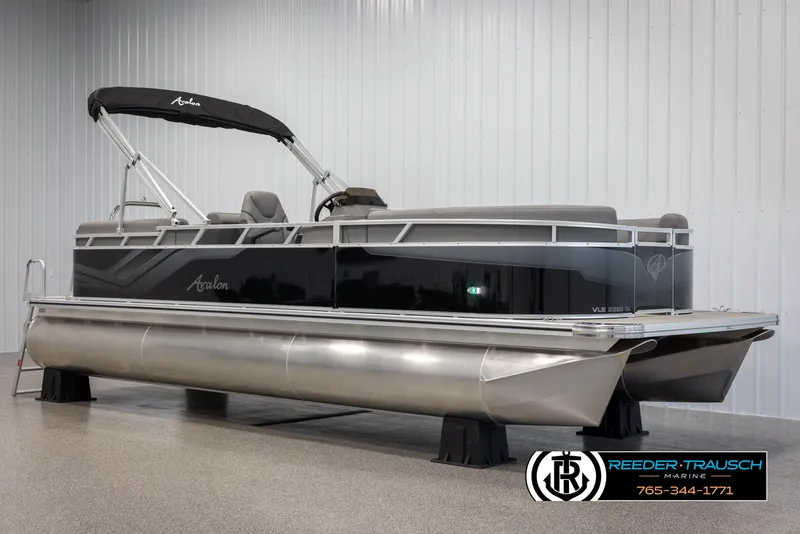 Slide: The Image of 2025 Avalon VLS QL pontoon boat in showroom, sleek design, black and silver finish. - 2