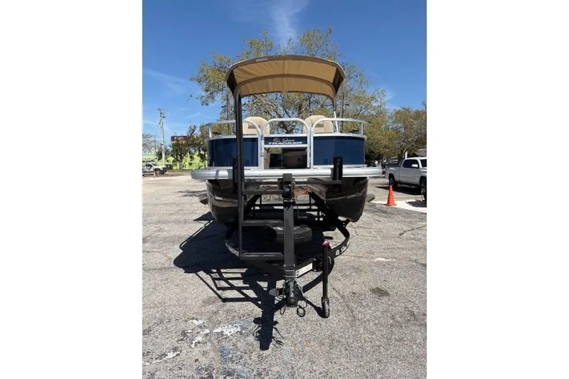 Slide: The Image of 2025 Sun Tracker Bass Buggy 16 XL Select pontoon boat on trailer, parked outdoors. - 4