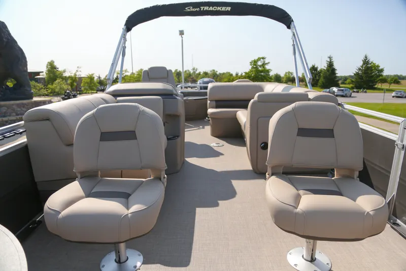 Slide: The Image of 2025 Sun Tracker Fishin' Barge 20 DLX interior with beige seating and open deck layout. - 2