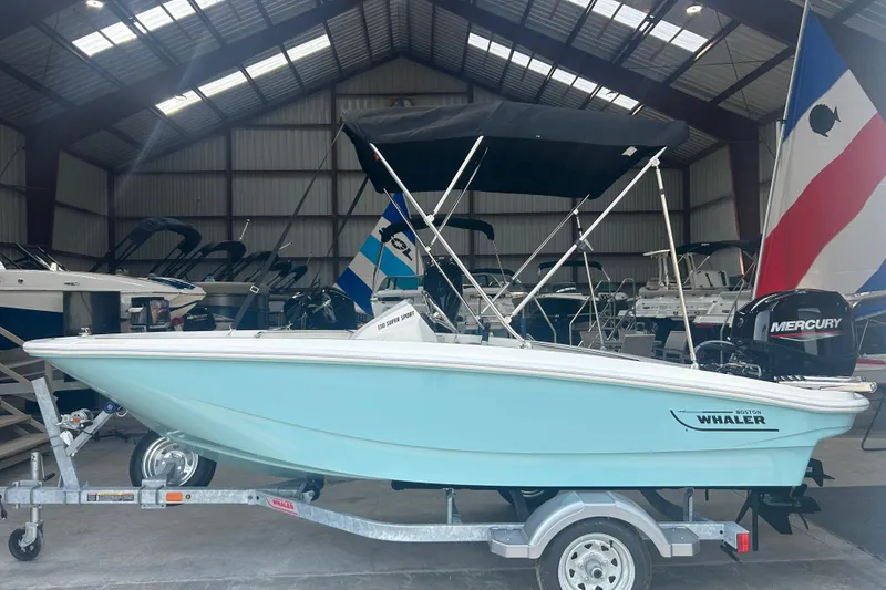 The Image of 2025 Boston Whaler 130 Super Sport boat in a showroom, featuring a Mercury engine. - 0