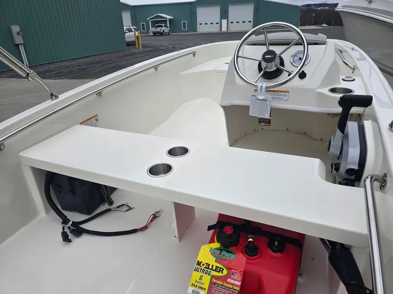 Slide: The Image of 2025 Boston Whaler 130 Super Sport boat interior with steering wheel and storage compartments. - 10