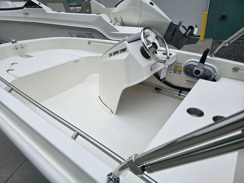 Slide: The Image of 2025 Boston Whaler 130 Super Sport boat interior with steering console and seating. - 11