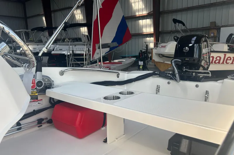 Slide: The Image of 2025 Boston Whaler 130 Super Sport boat interior with motor and seating in a storage facility. - 5