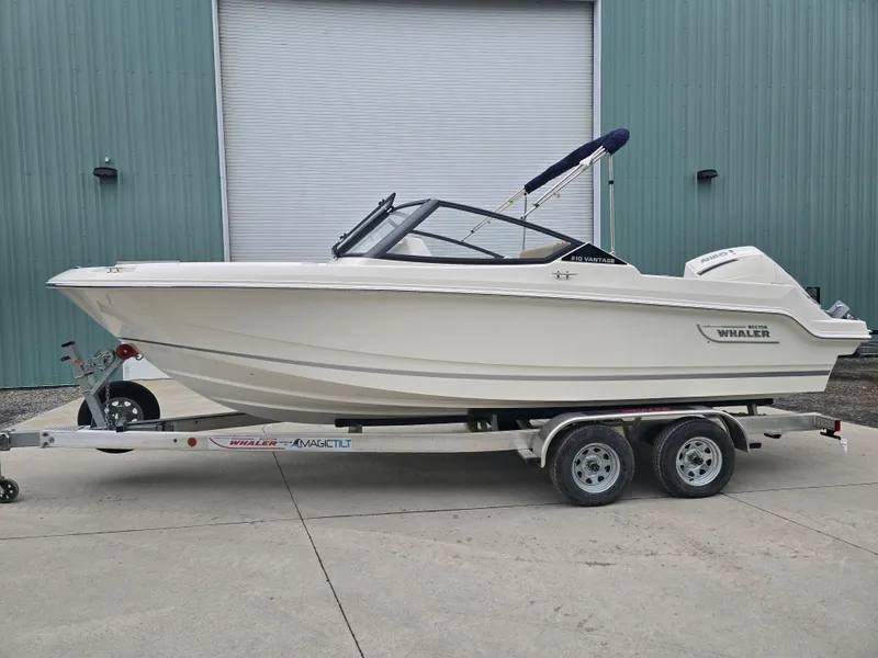The Image of 2025 Boston Whaler 210 Vantage boat on trailer, parked outside a warehouse. - 1