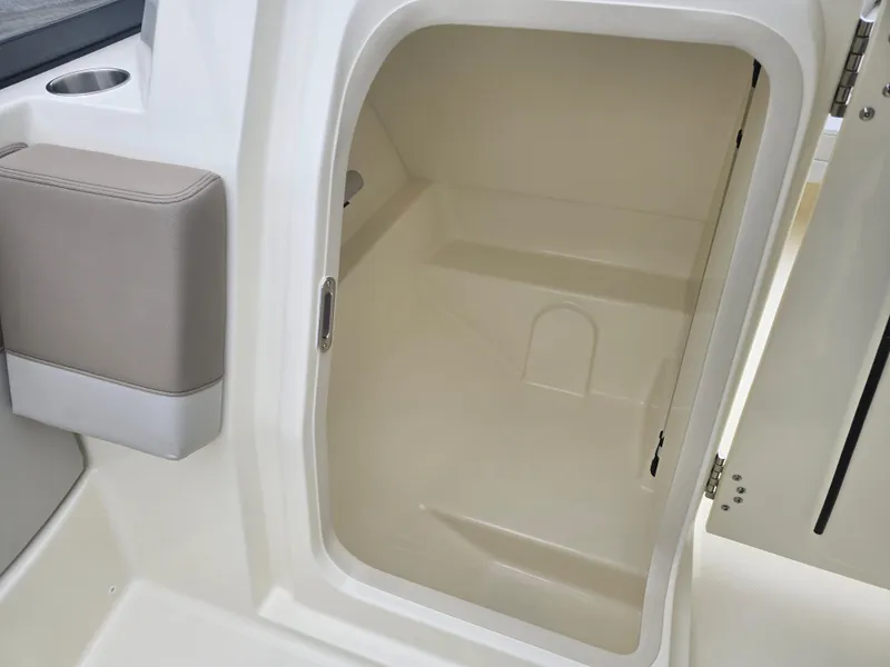 Slide: The Image of 2025 Boston Whaler 210 Vantage storage compartment, open door, beige interior. - 16