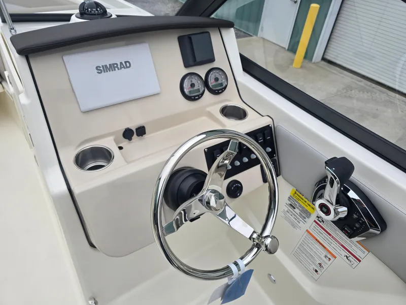 Slide: The Image of 2025 Boston Whaler 210 Vantage boat dashboard with steering wheel and Simrad display. - 23