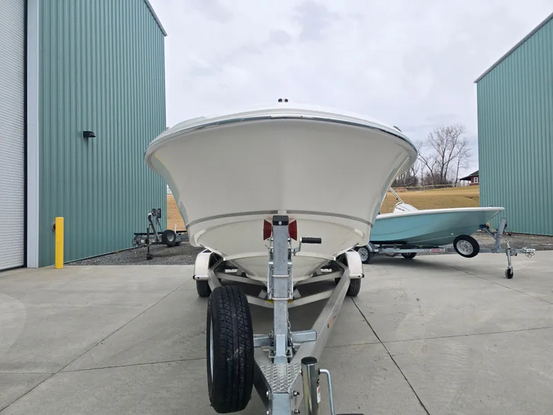 Slide: The Image of 2025 Boston Whaler 210 Vantage boat on trailer, parked between green buildings. - 31