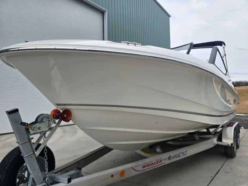 Slide: The Image of 2025 Boston Whaler 210 Vantage boat on trailer, parked near a building. - 32