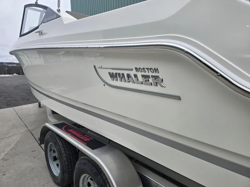 Slide: The Image of 2025 Boston Whaler 210 Vantage boat on trailer, side view showing logo and sleek design. - 8