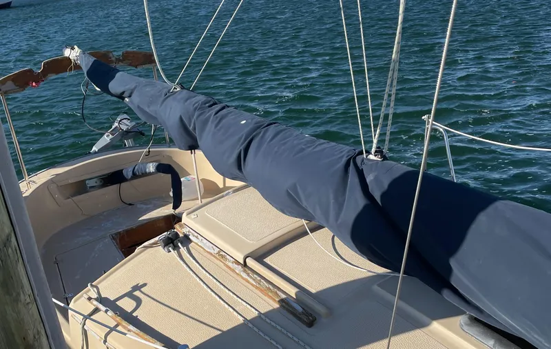 Slide: The Image of 2004 Com-Pac 17 Suncat sailboat with covered boom, docked on calm water. - 2