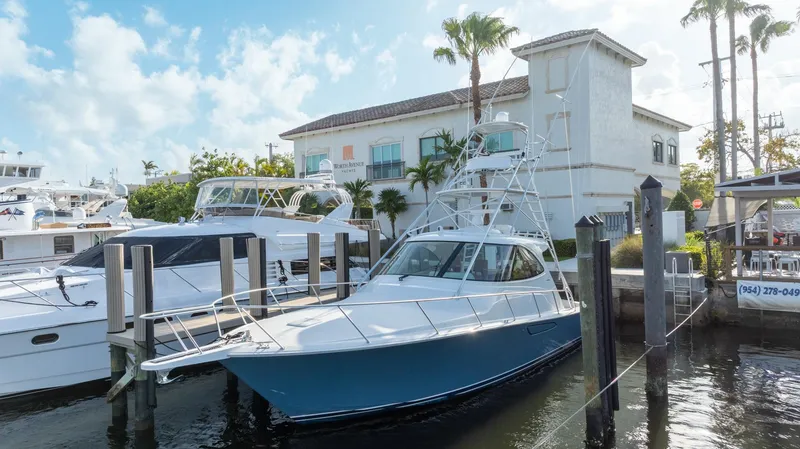 Slide: The Image of 2014 Viking Sport Tower yacht docked at marina, surrounded by palm trees and buildings. - 2