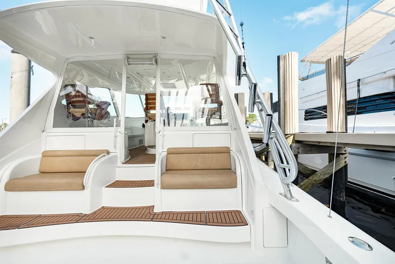 Slide: The Image of 2014 Viking Sport Tower yacht with cushioned seating and sleek design at a marina. - 9