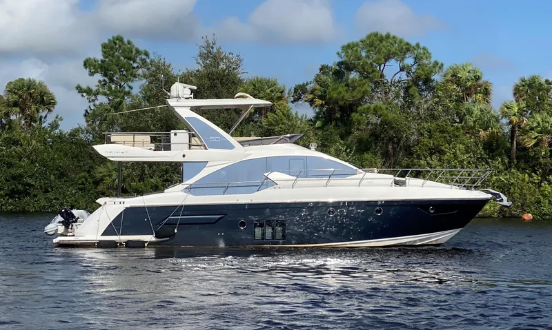 Slide: The Image of 2015 Azimut 50 Fly yacht cruising on a serene waterway with lush greenery. - 0