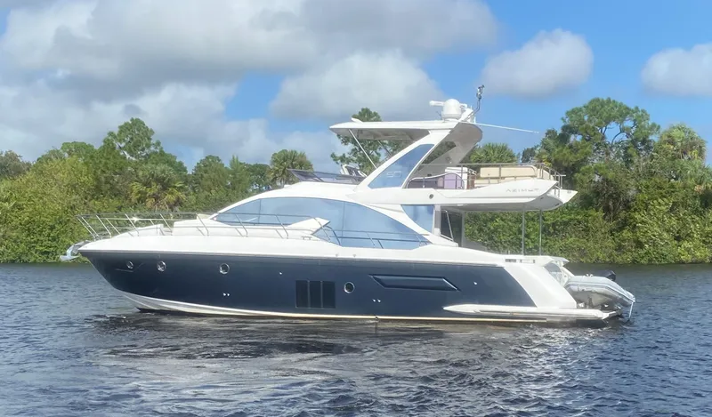 Slide: The Image of 2015 Azimut 50 Fly yacht on a serene waterway, surrounded by lush greenery. - 1