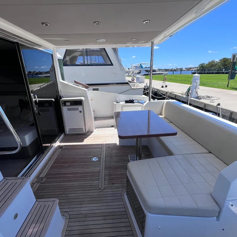 Slide: The Image of Azimut 50 Fly 2015 yacht deck with seating and table, docked by the water. - 34