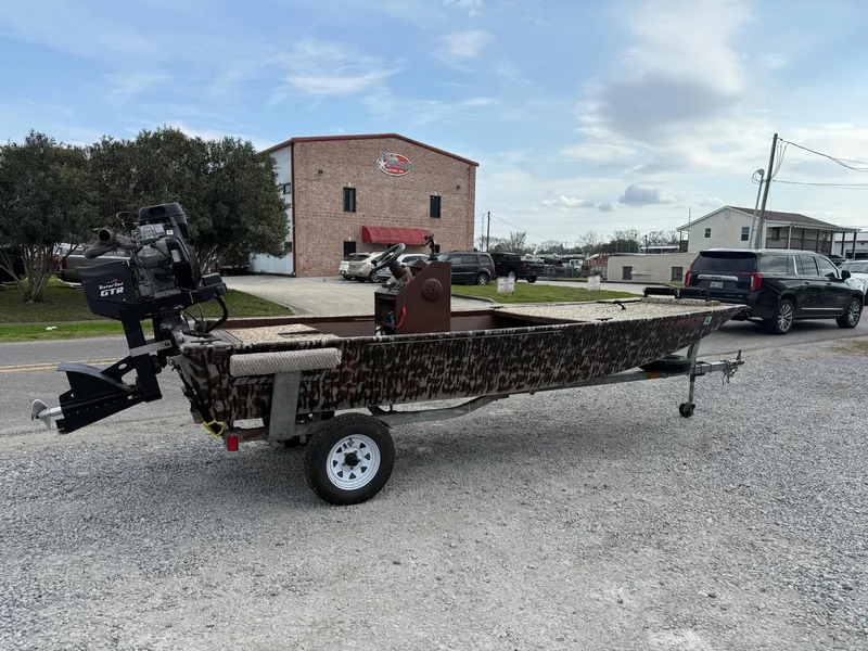 Slide: The Image of 2016 Gator Tail 1648 boat on trailer, parked outdoors near buildings and vehicles. - 3