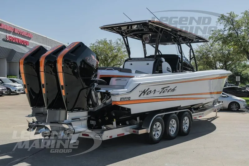 Slide: The Image of 2025 Nor-Tech 340 Sport boat on trailer with triple engines, parked outdoors. - 4