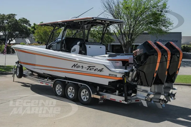 Slide: The Image of 2025 Nor-Tech 340 Sport boat with triple outboard engines, rear view in a parking lot. - 5