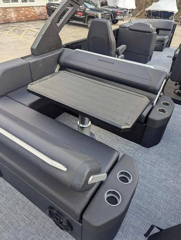 Slide: The Image of 2025 Berkshire 23ULE boat interior with gray seating and table, featuring cup holders. - 2