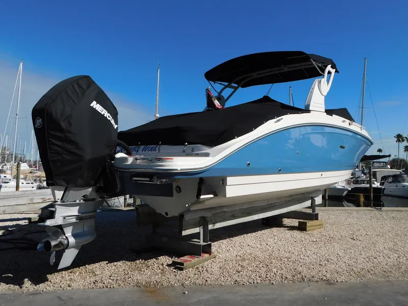 Slide: The Image of 2020 Sea Ray SDX 270 Outboard boat with blue hull, docked on a gravel surface. - 2