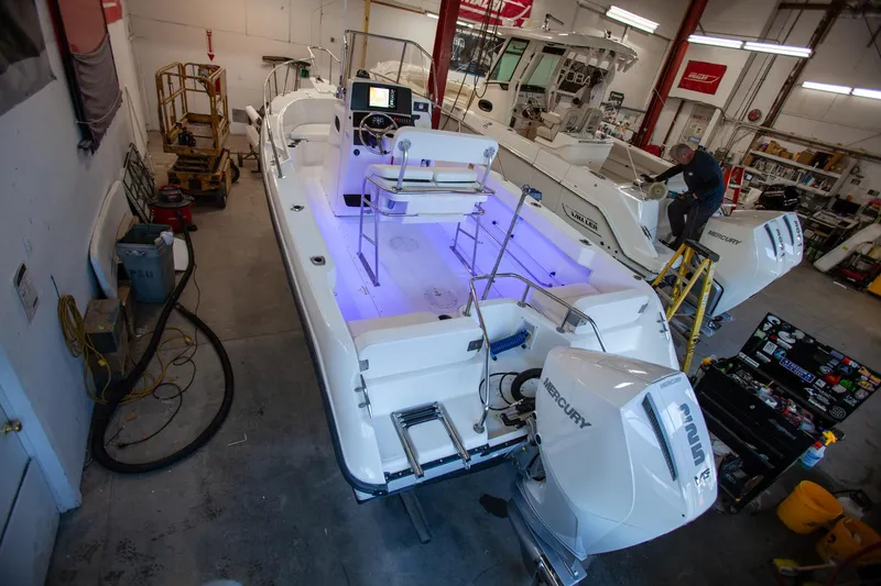 Slide: The Image of 2000 Boston Whaler 210 Outrage boat in workshop, featuring Mercury engine and illuminated interior. - 7