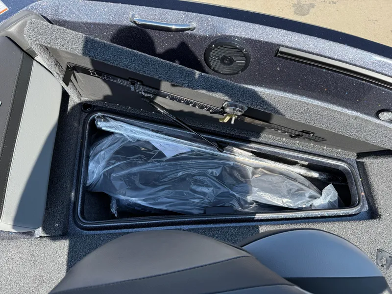 Slide: The Image of 2025 Lund 202 Pro-V GL boat storage compartment with open lid and protective cover. - 10