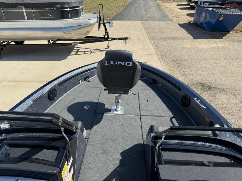 Slide: The Image of 2025 Lund 202 Pro-V GL boat interior with seating and deck, parked on a trailer. - 12