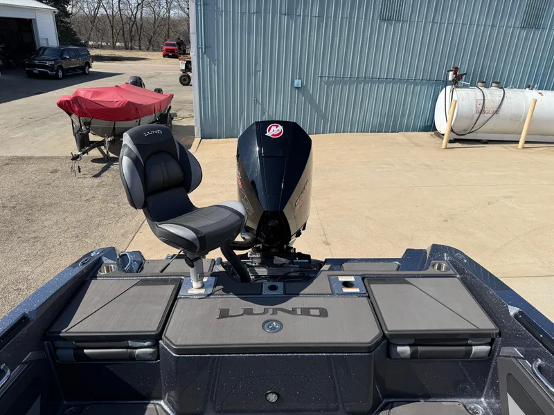 Slide: The Image of 2025 Lund 202 Pro-V GL boat with motor and seating, parked outdoors. - 29