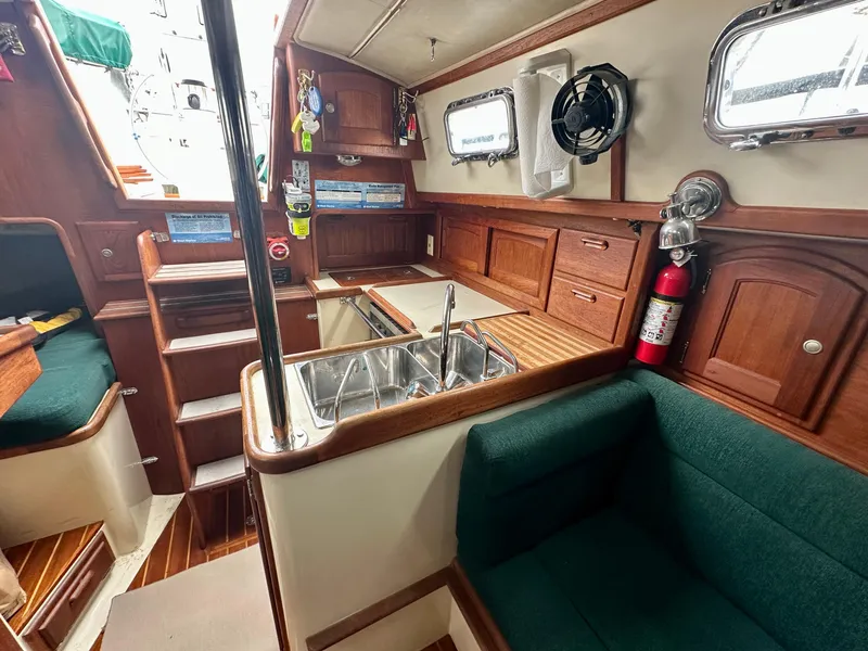 Slide: The Image of Interior of 1998 Pacific Seacraft Cutter sailboat with wood cabinetry and green seating. - 10