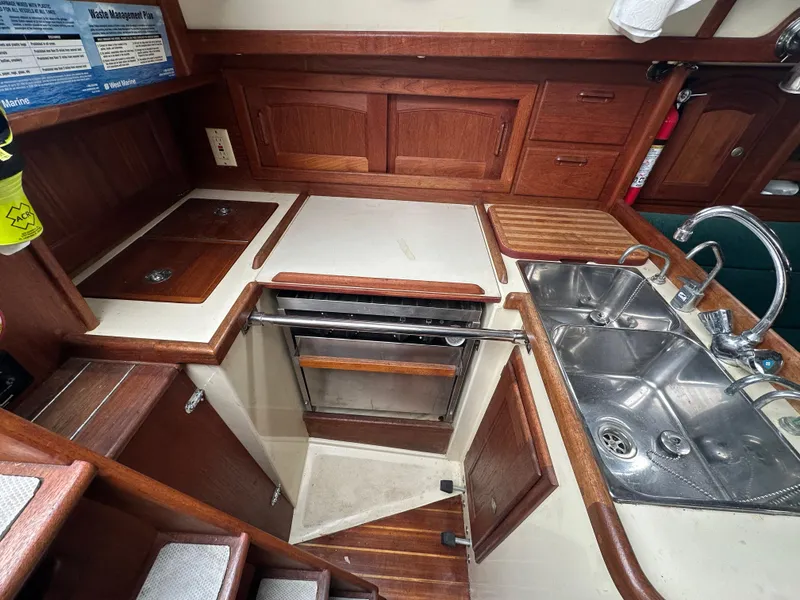 Slide: The Image of 1998 Pacific Seacraft Cutter galley with wood cabinetry, stainless steel sink, and compact stove. - 11